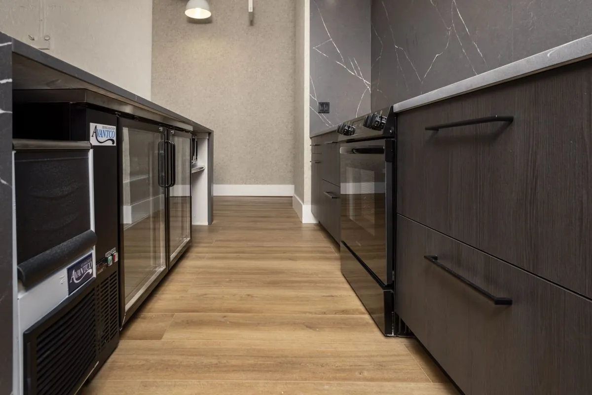 Kitchen aisle with ice machine, under-counter refrigerator, and oven