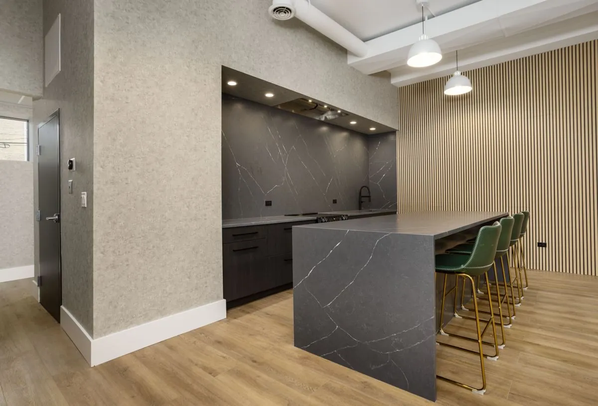 Kitchen island with a waterfall marble edge and green bar stools