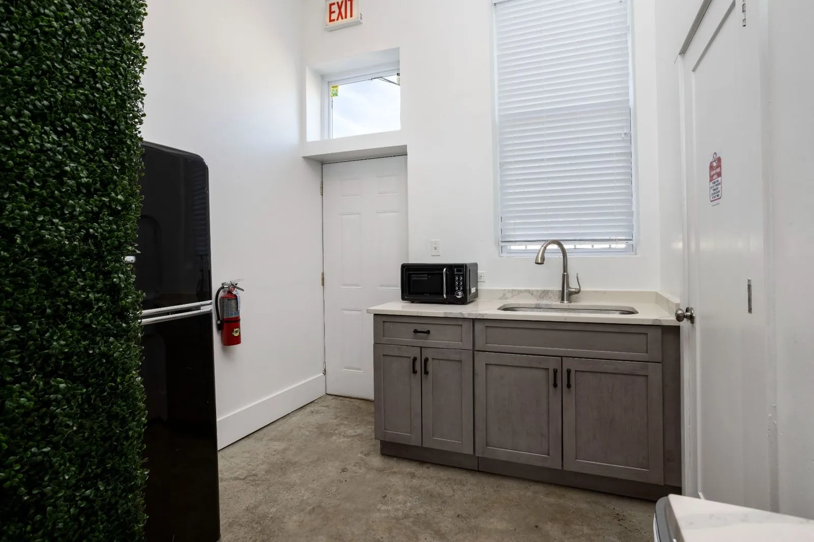 Kitchenette with sink, microwave, gray cabinets, and refrigerator