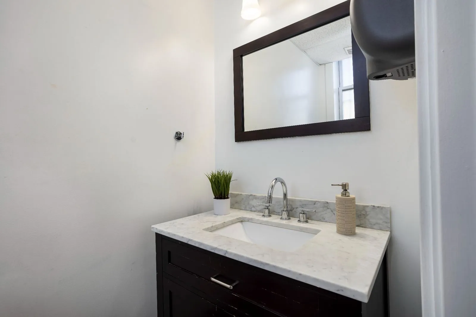 Restroom with a marble vanity and framed mirror