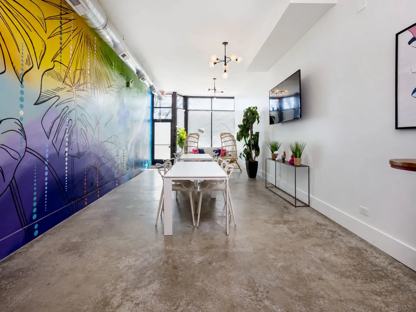 Long view of Nala’s Party Room along the tropical mural toward the front windows and lounge