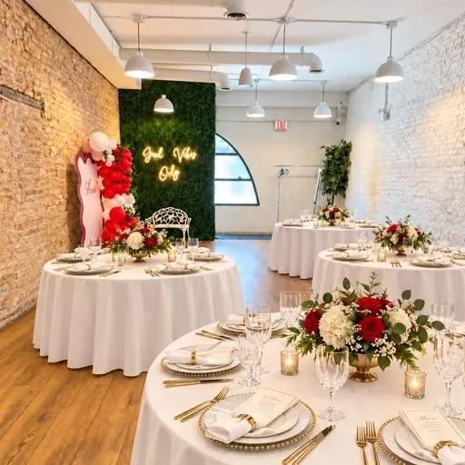 Round tables set with white linens and red and white flowers at Montrose Studio in Portage Park